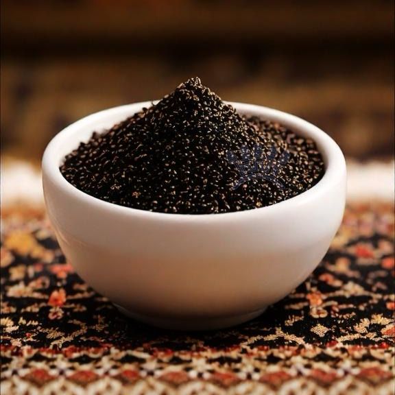 Licorice extract granules in a white bowl on a patterned surface, showcasing Sepidan Osareh Jonoob's premium herbal product